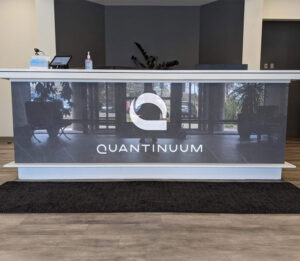Custom Acrylic Signs displayed on a reception desk featuring a company logo, creating a professional and modern office branding experience. Reception Desk Signs